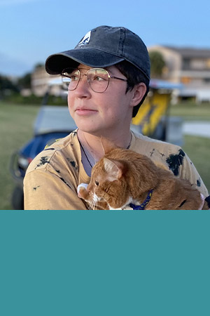 Student in glasses and hat holding cat