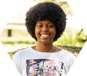 Student wearing necklace, standing in front of tree