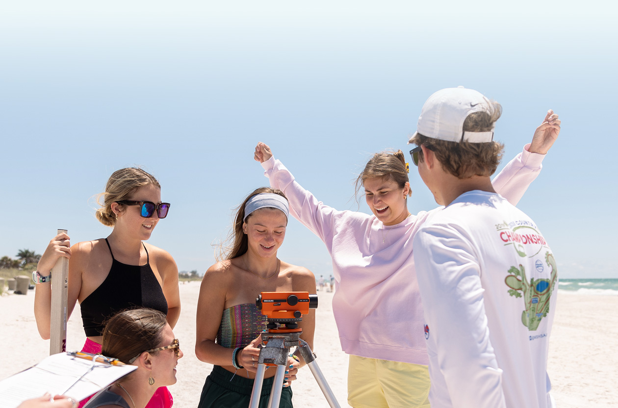 A group of students uses scientific equipment on the beach