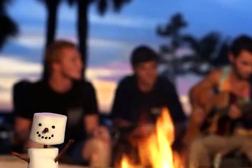 Snowman made of marshmallows with students around campfire in background