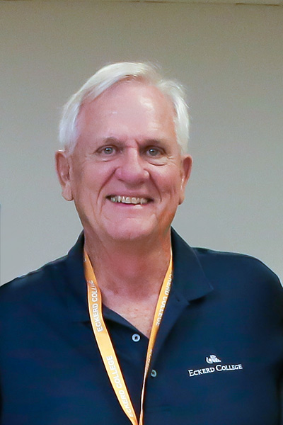 Gentleman wearing a shirt that reads Eckerd College and a yellow ribbon around his neck