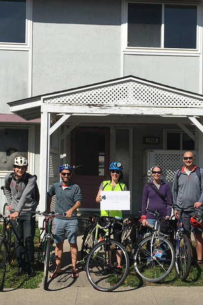 Sarah with friends on their bikes in front of building