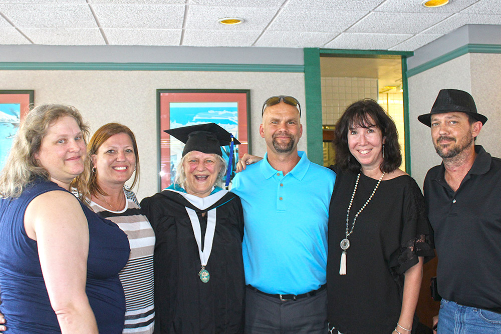 Chrissy Jackson in graduation cap with five family members around her