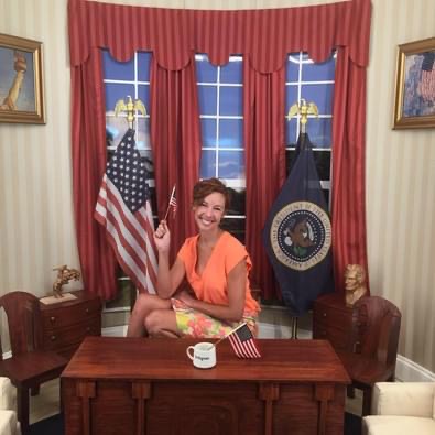 Woman sits in a miniature room with American flag