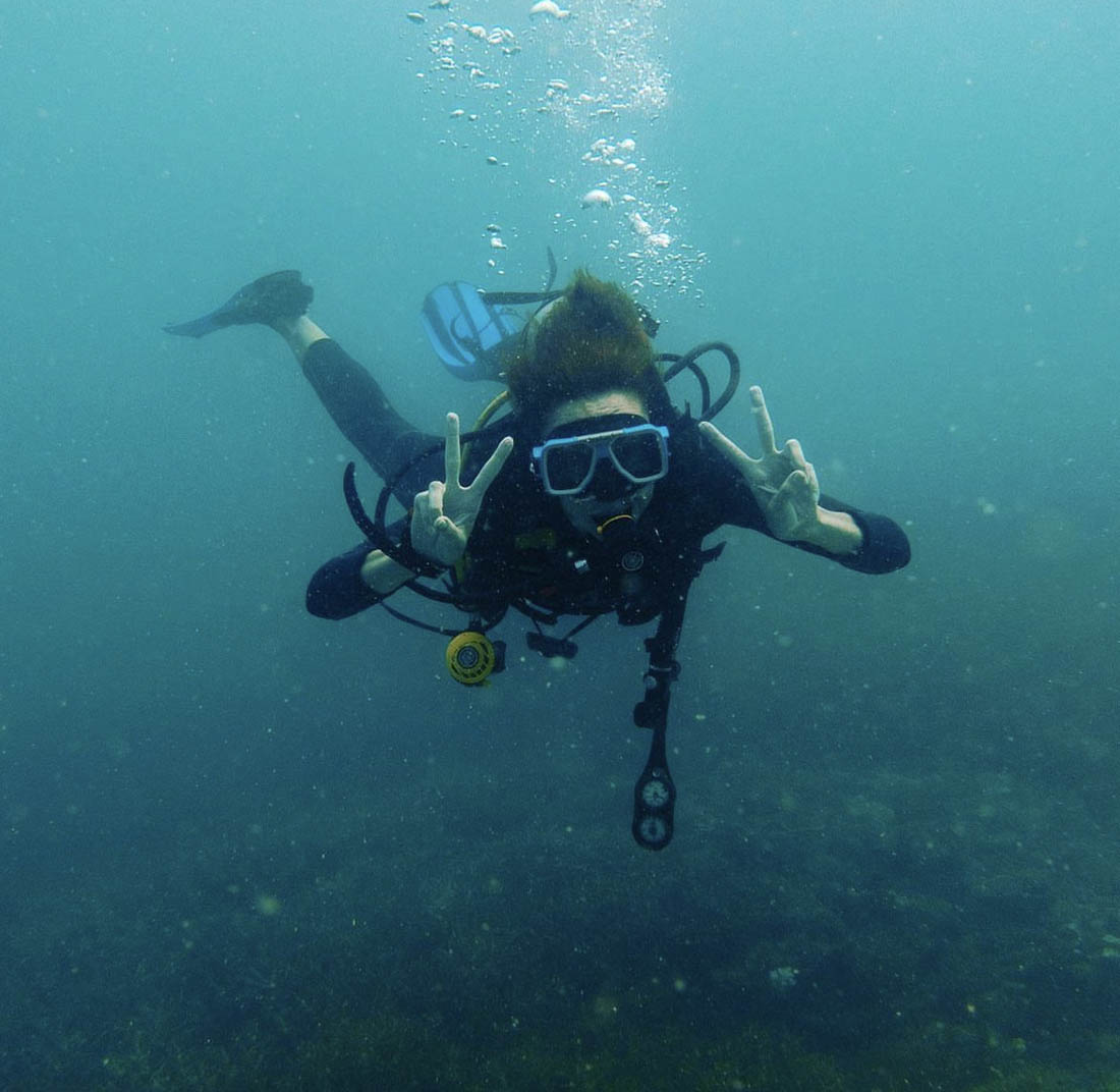 Person scuba diving while giving two peace signs