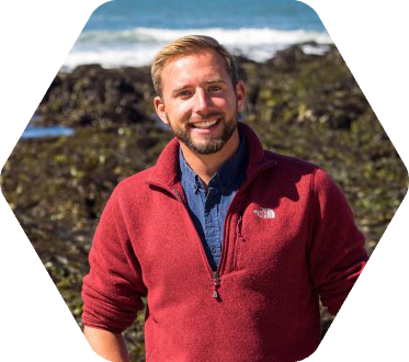Man standing in front of surf breaking on coastline
