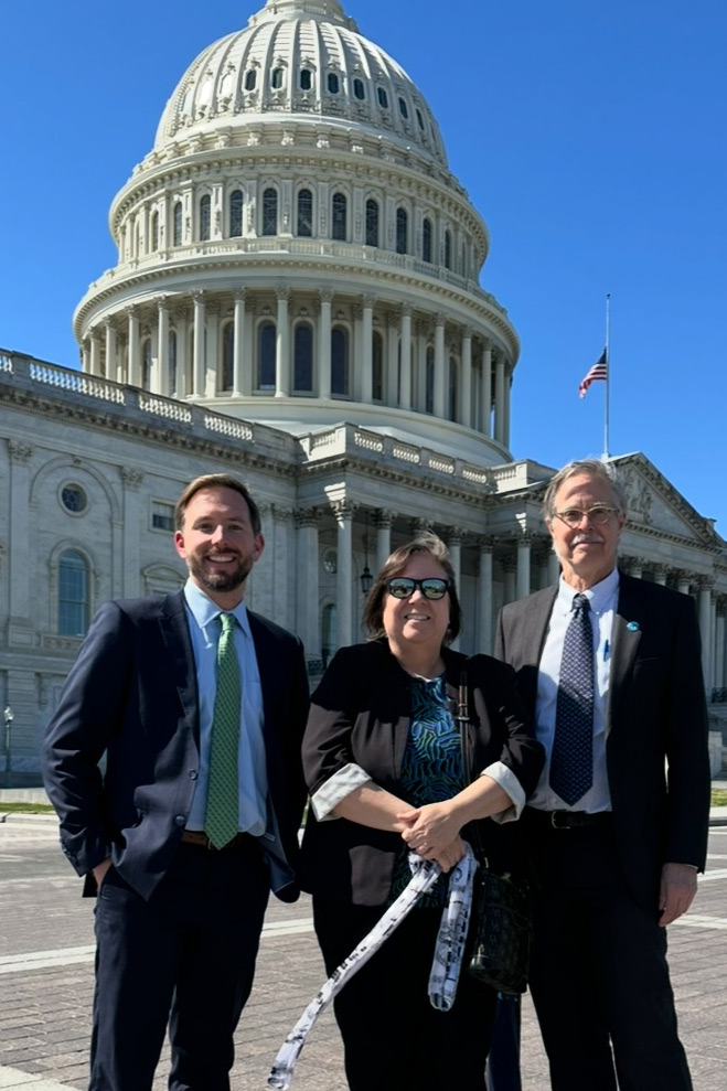 Three people in formal attire standing outside government building