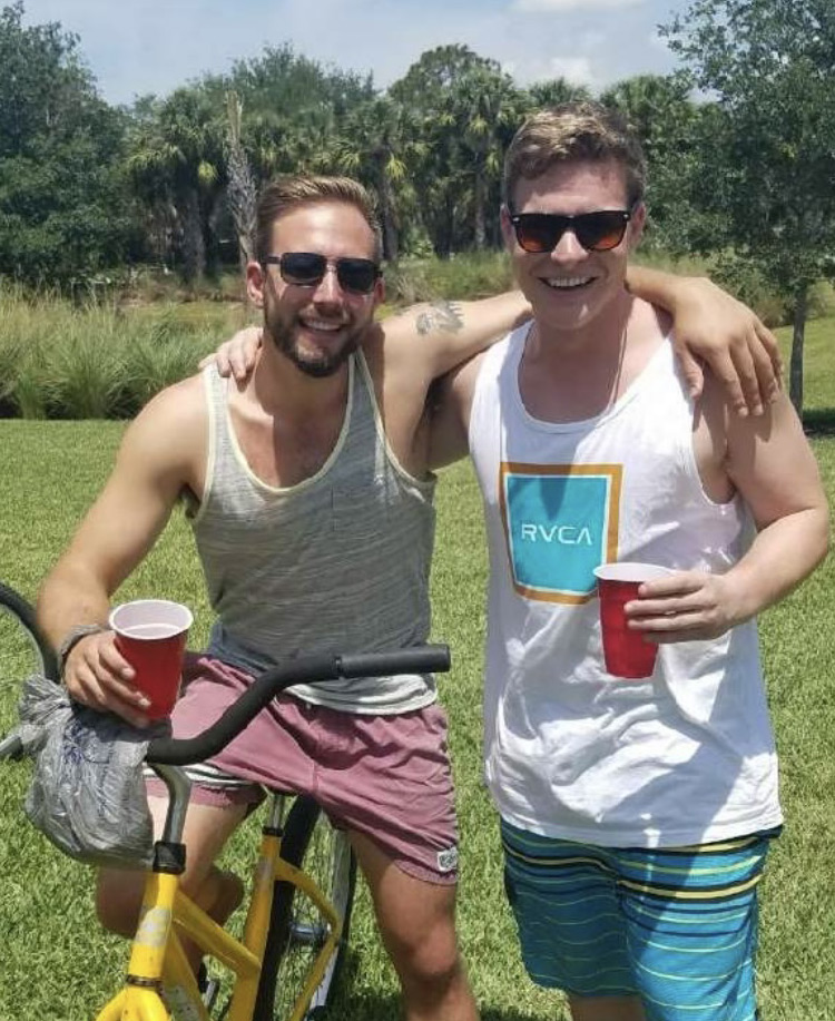Two students with arms over shoulders with yellow bike