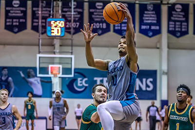 Basketball player doing a lay-out white defenders watch