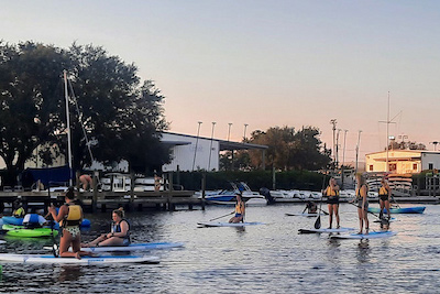 Students on paddleboards and in kayaks on the water during dusk