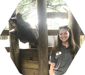 Student standing in zoo with rhino behind her