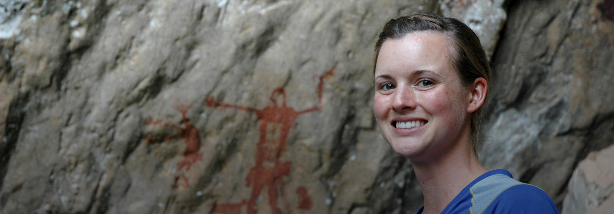 Student standing in front of rock art in Thailand.