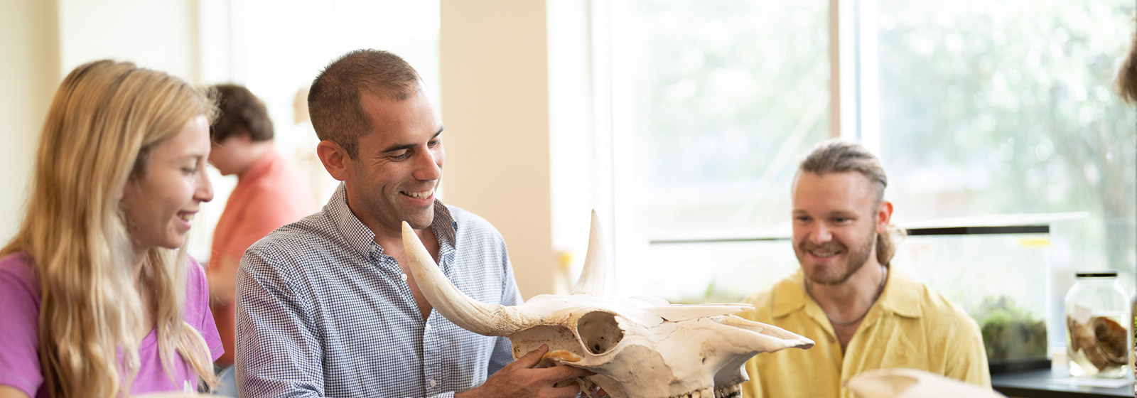 Professor Goessling looks at an animal skull in a lab with biology students