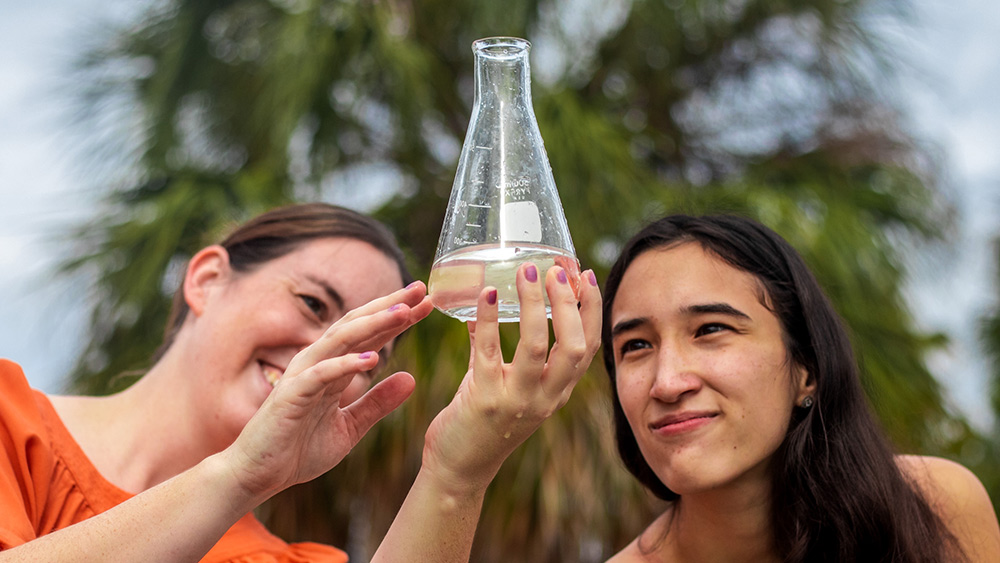Professor and student look at clear vial together
