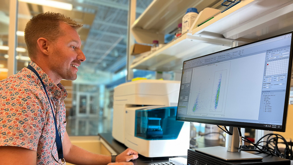 Professor sits in lab in front of high-tech equipment