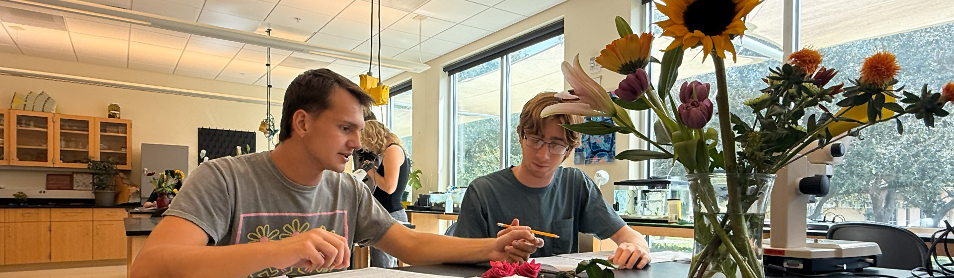 Two students at a lab table doing biology research with plants