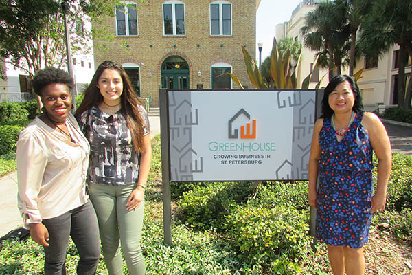 Two Eckerd College students stand with employer in front of storefront