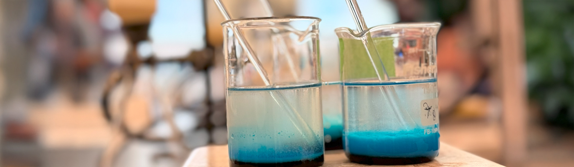 Two beakers on a hot plate containing a bright blue liquid solution