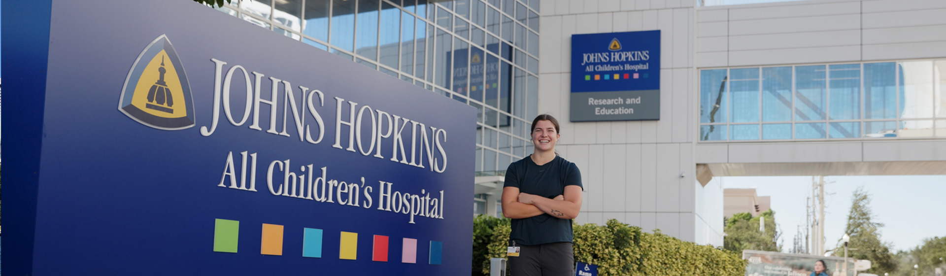 Student stands proudly in front of sign that reads JOHNS HOPKINS All Children's Hospital