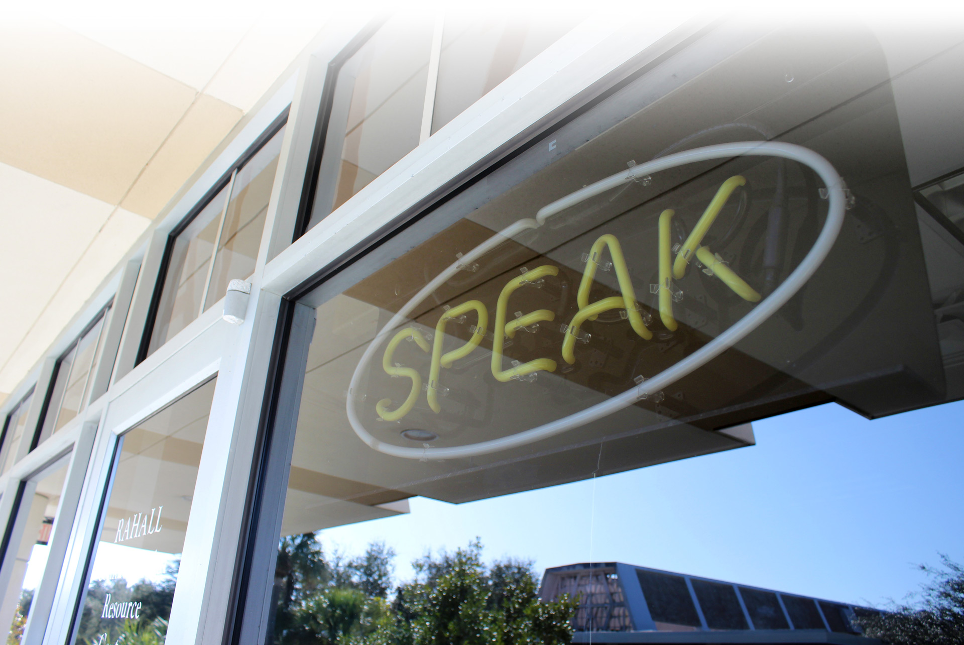 A neon sign in a window that reads SPEAK