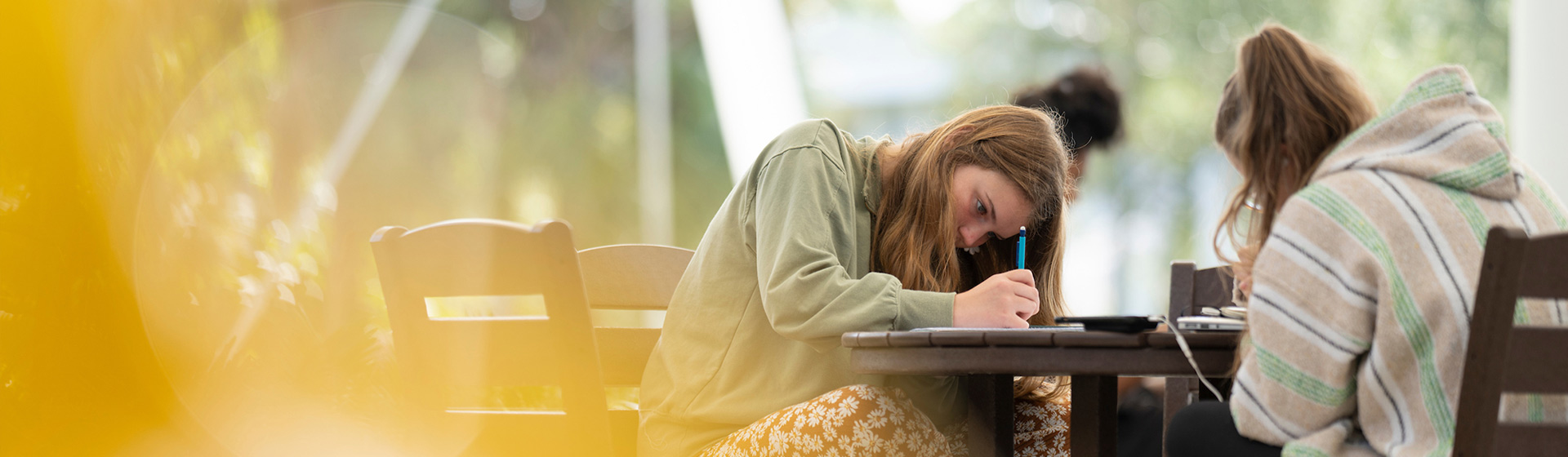 Student leans over a table while writing intently