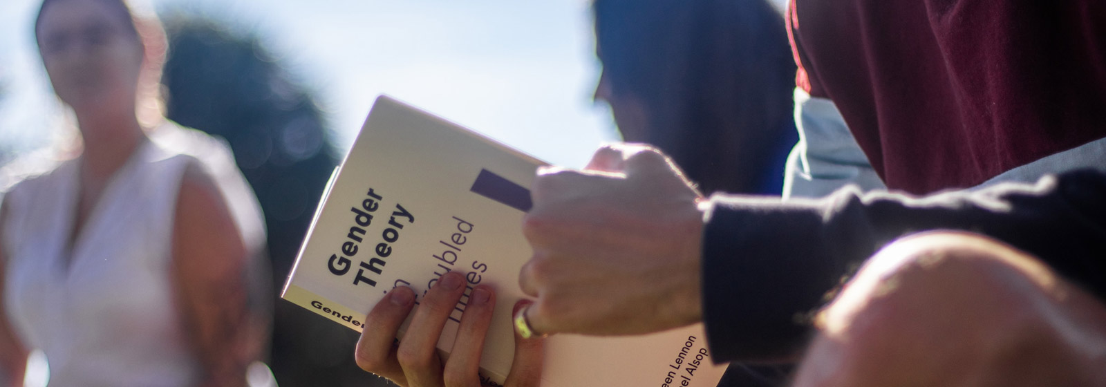 Eckerd student's hands holding a book with title "Gender Theory"