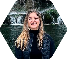 Student in jacket seated in front of waterfall