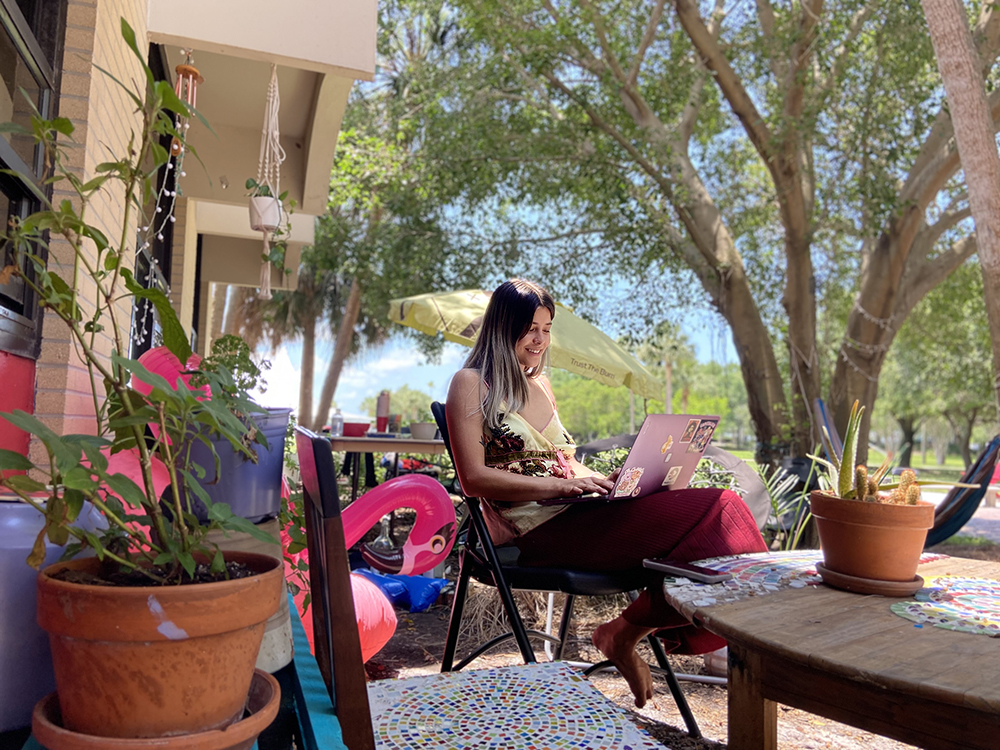 Student studying outside of Kappa complex surrounded by plants, hammock and pool float