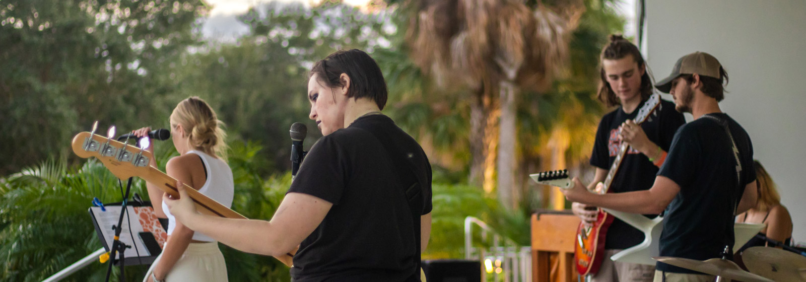 Four students play instruments and sing outdoors