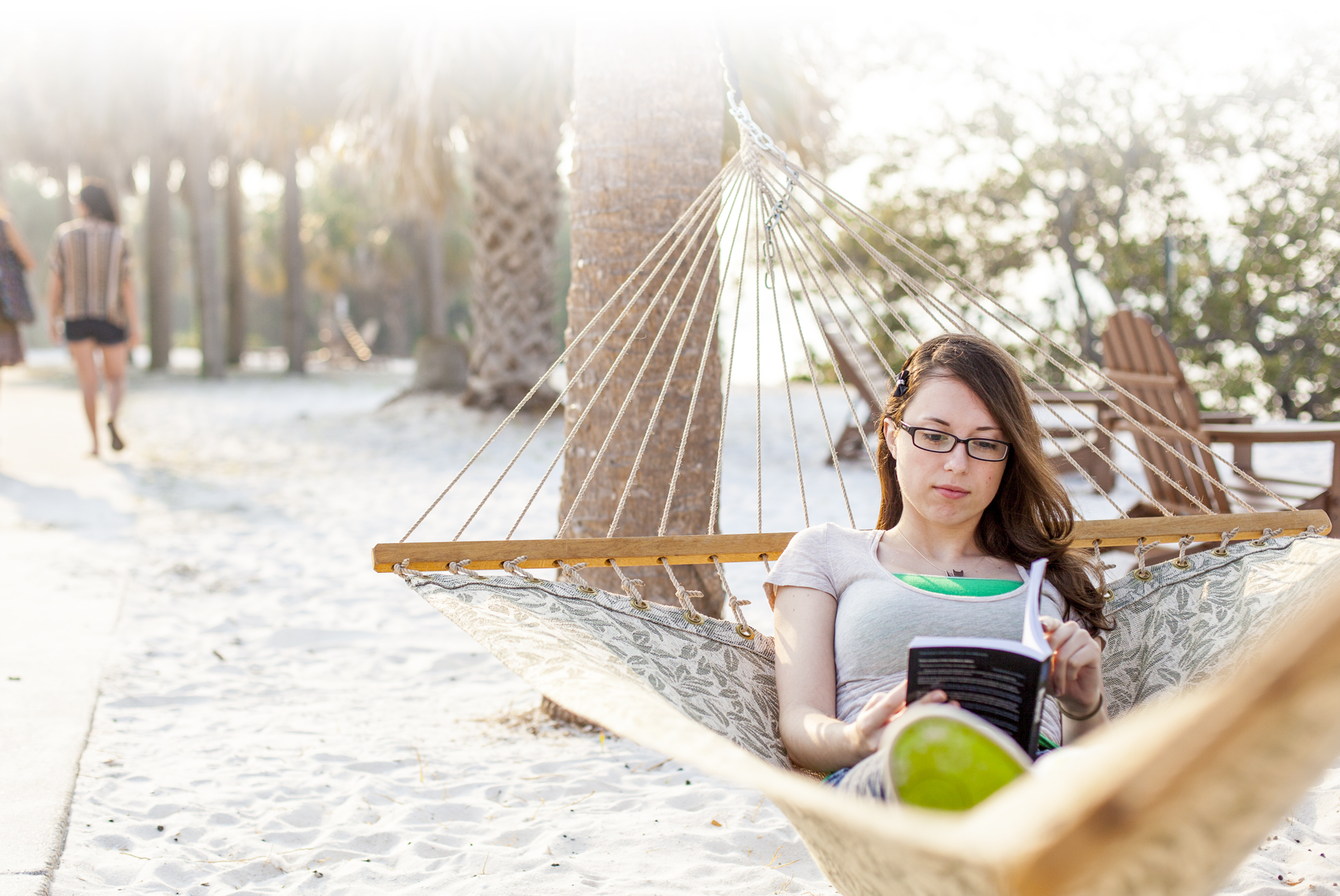 Literature degree seeking student reads a book in a hammock on Eckerd College South Beach