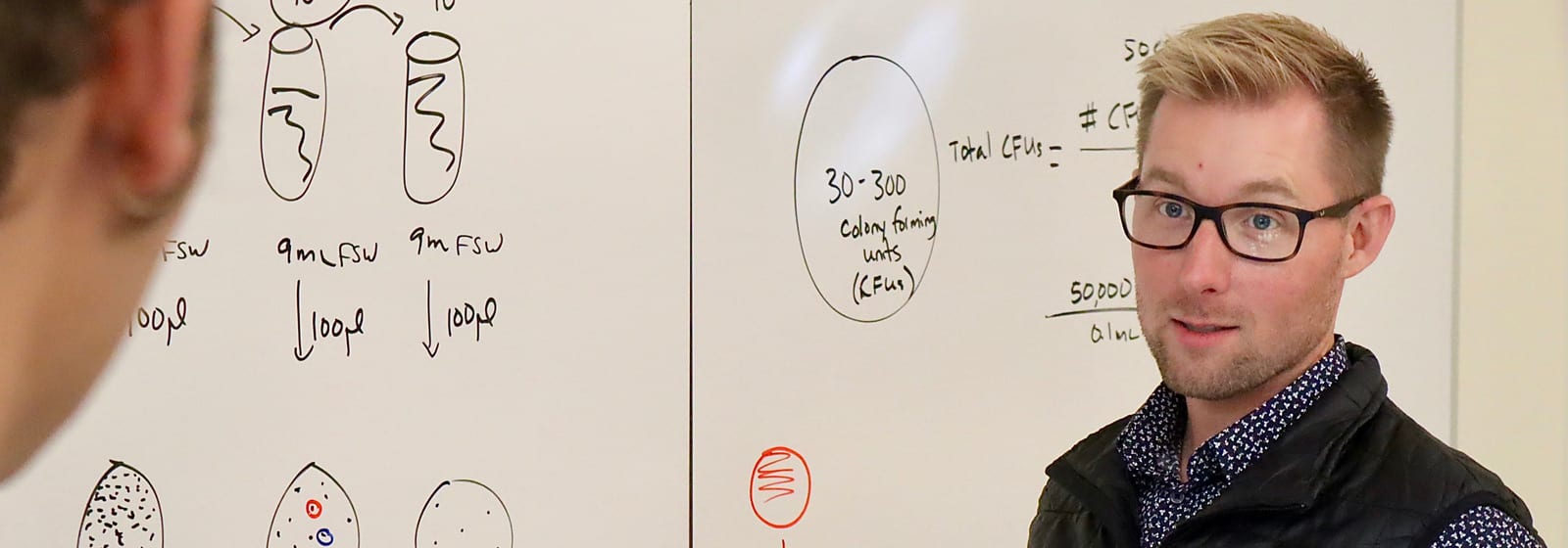 Professor at board talking with student