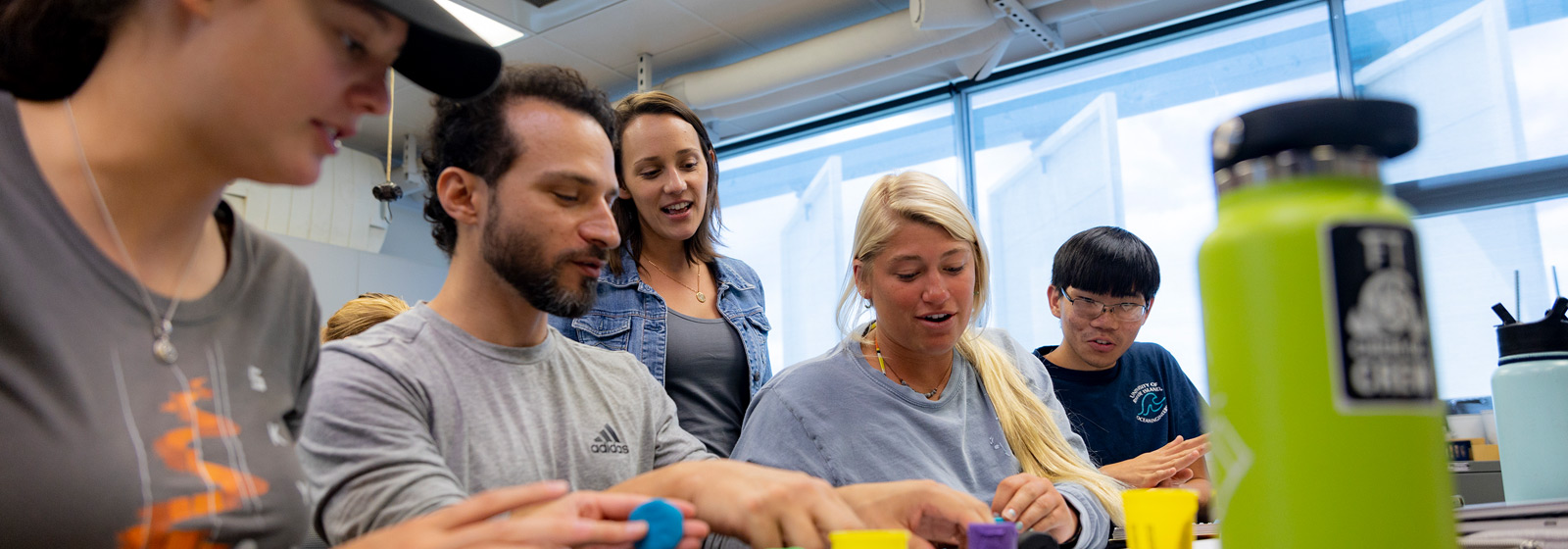 Professor standing behind students working at a lab table