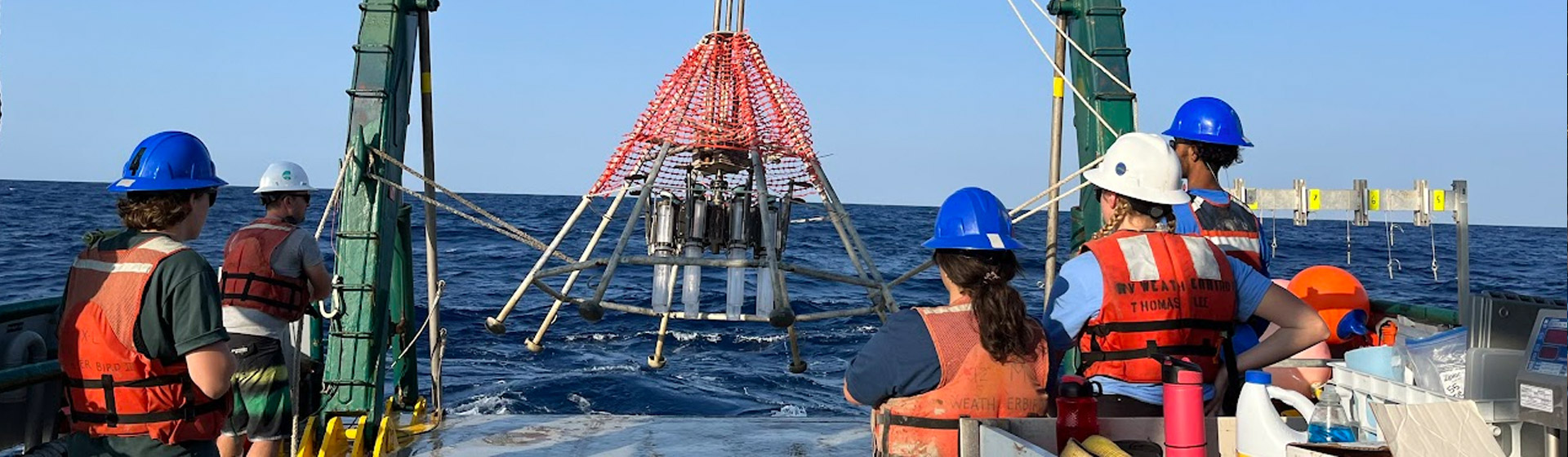 Students wearing helmets while doing research on a research vessel