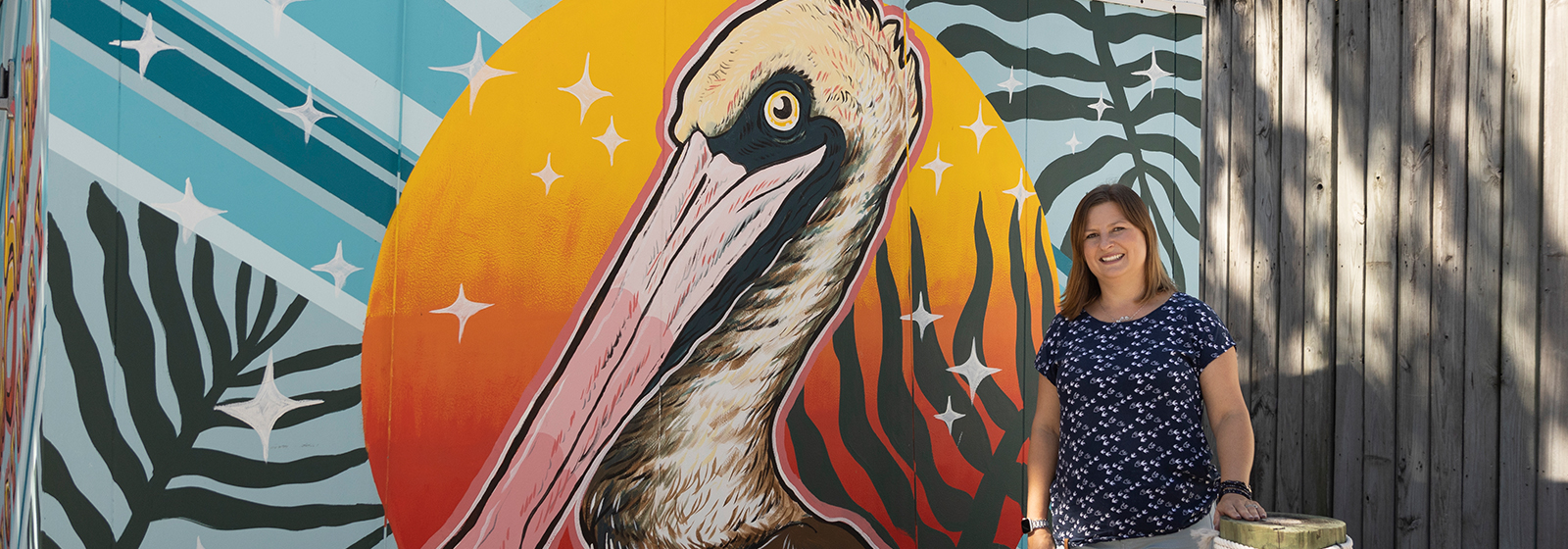 Professor standing before mural of brown pelican