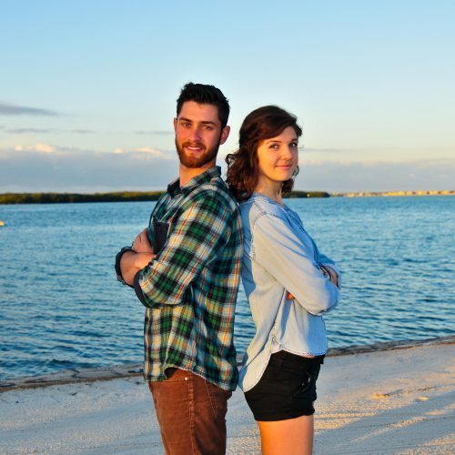 Henry Ashworth and Sidney Fulford stand back to back with arms crossed on Eckerd College's South Beach.