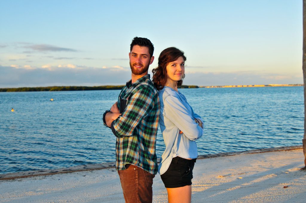 Henry Ashworth and Sidney Fulford stand back to back with arms crossed on Eckerd College's South Beach.
