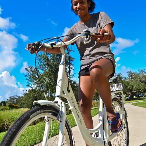 Female student rides new bicycle provided by On Bike Share for students to take off campus.