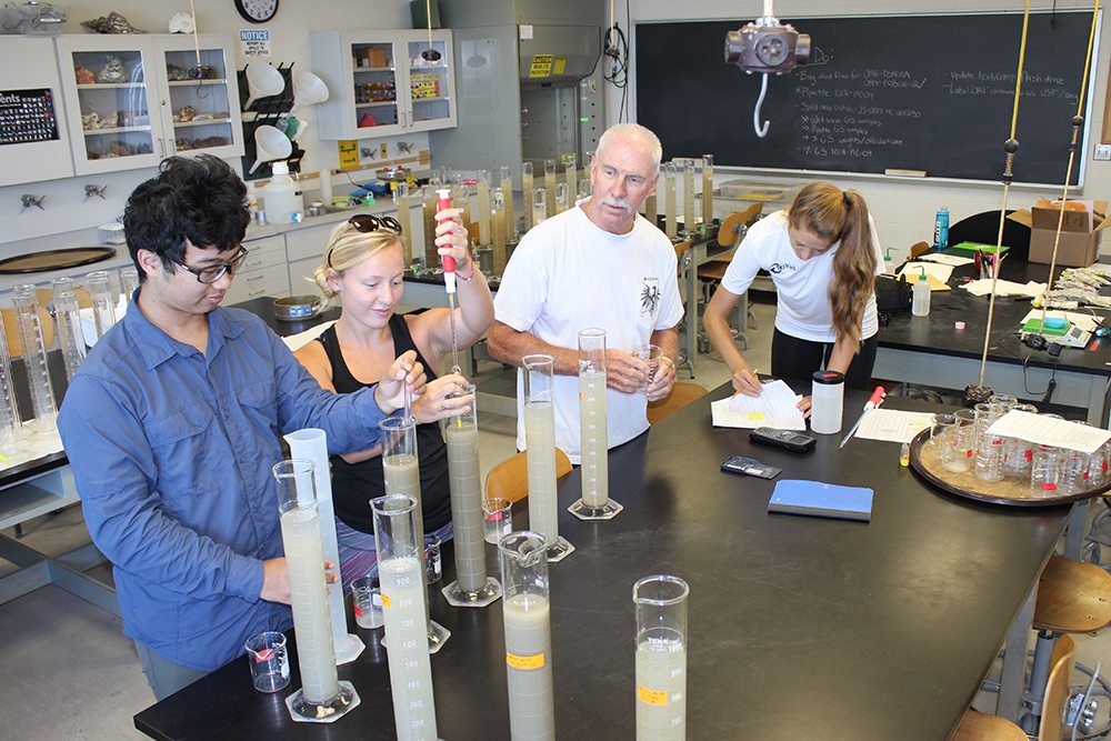 Dr. Brooks and students around a table with lab equipment