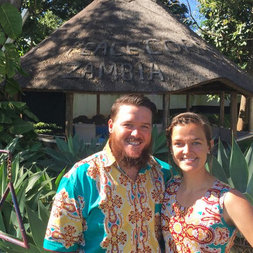 Couple standing in front of hut-like home