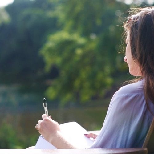 Creative Writing student writing on the beach