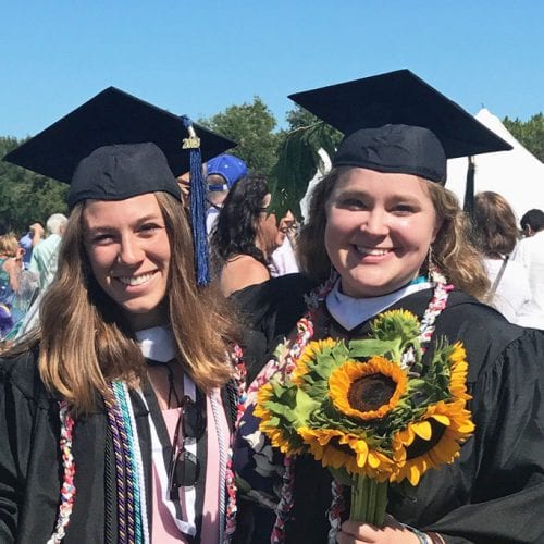 Francesca Larrain and Anna Lindquist standing with plastic honor cords at Commencement