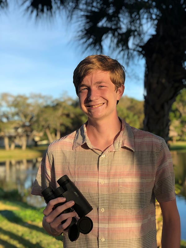Eckerd student holding binoculars