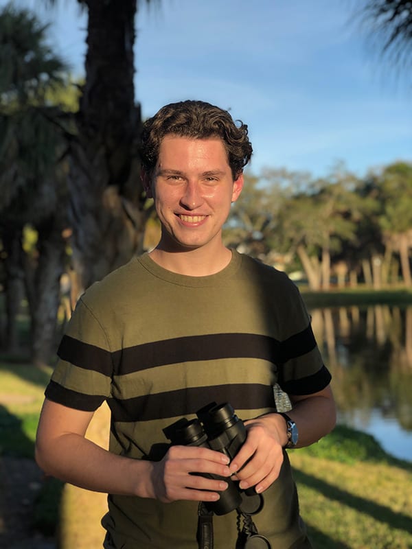 Eckerd student holding binoculars