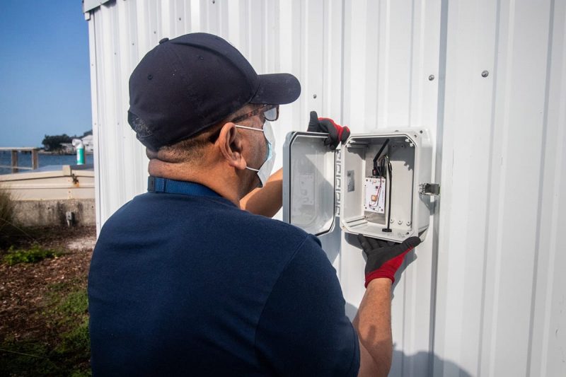 Staff installing box on side of shed