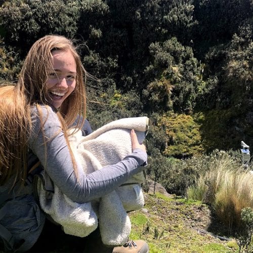 Student seated on side of ravine in forest