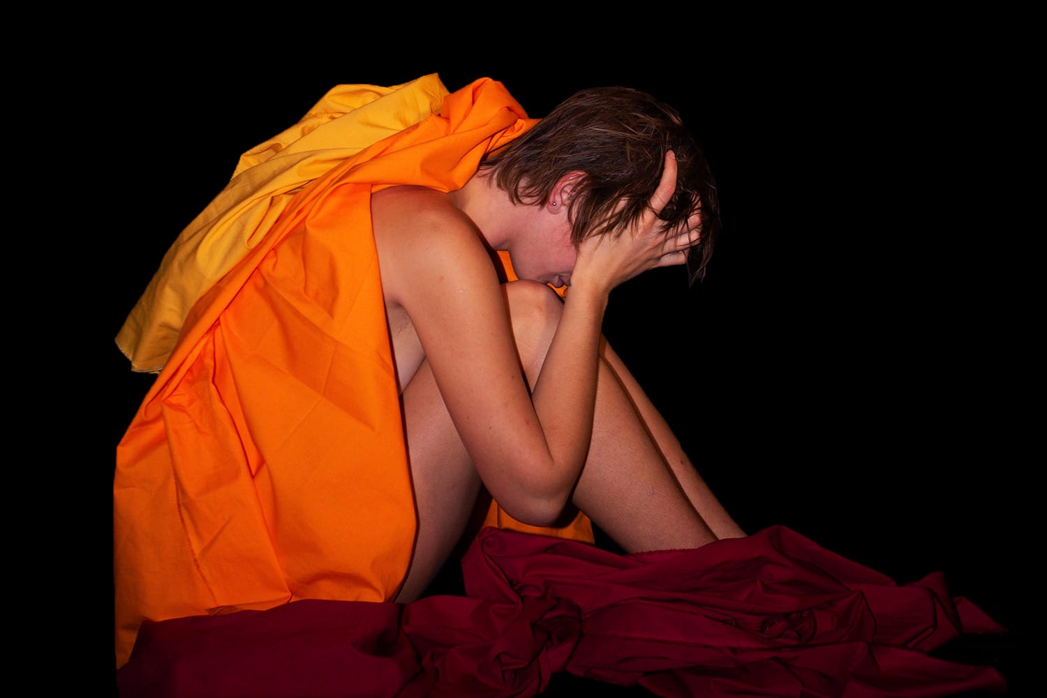 Woman in robes sitting with hands over face