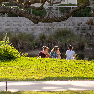 Eckerd College students seated at the edge of a pond in Florida