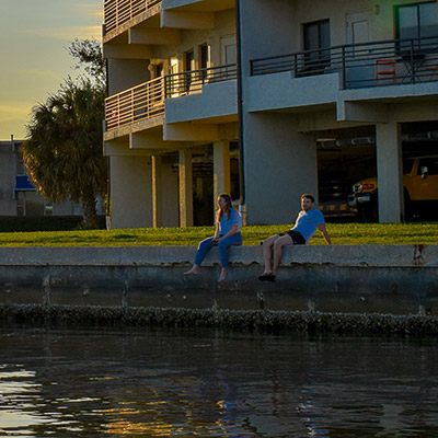 Students sit along the seawall next to the Omega residence hall at Eckerd College