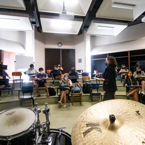 Professor teaching with drums in foreground and students seated