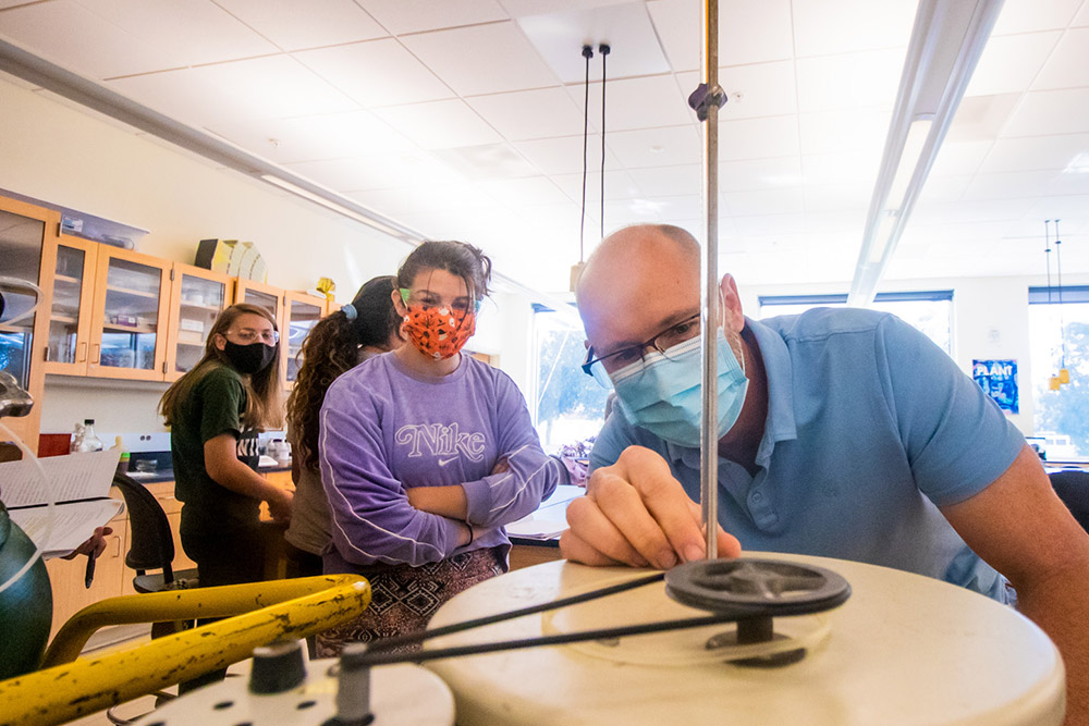 Professor Larkin leans in to adjust equipment